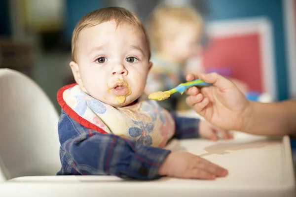 Een baby-kind eet voedsel met moeder lepel — Stockfoto