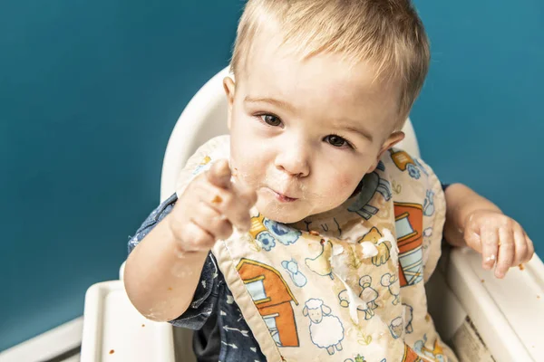 En bedårande baby pojke med en röra med flingor på köket — Stockfoto