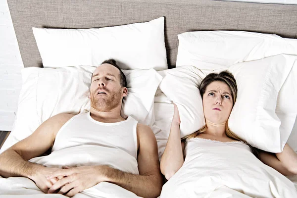 Woman blocking ears while man snoring on bed — Stock Photo, Image