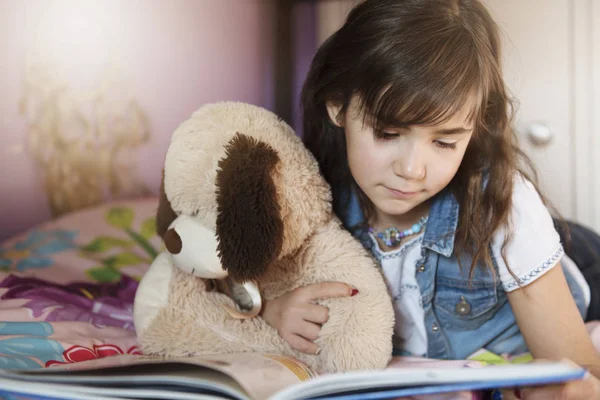 7-річна дівчинка читає книгу на ліжку — стокове фото