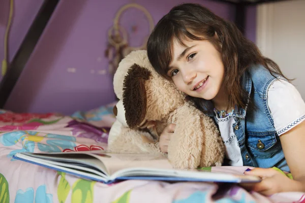 7-річна дівчинка читає книгу на ліжку — стокове фото