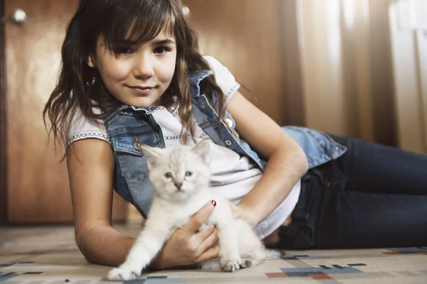 7 år gammal tjej med kattunge hemma på köksgolvet, — Stockfoto