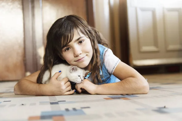 7-jähriges Mädchen mit Kätzchen zu Hause auf dem Küchenboden, — Stockfoto