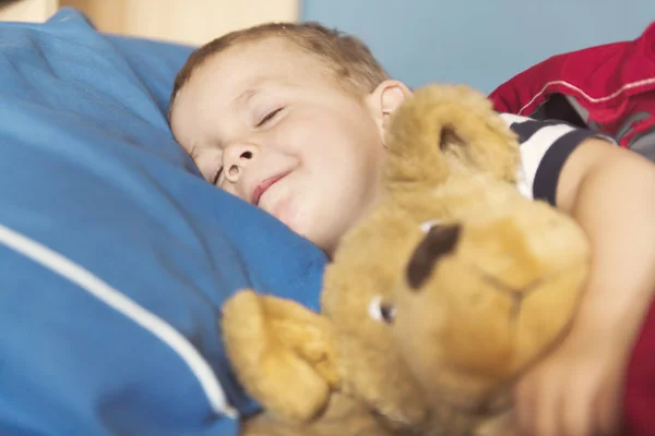 Barn som sover i sin säng med teddy — Stockfoto