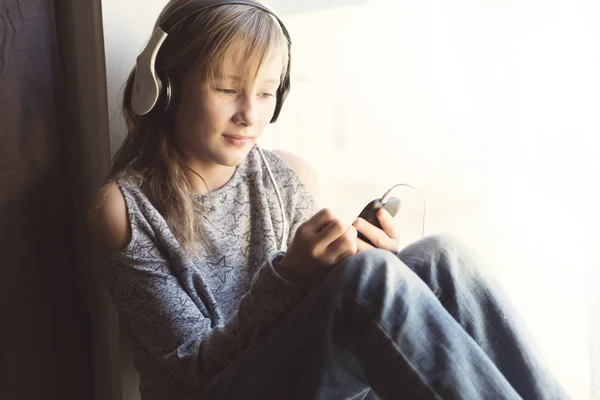 Jovem 10 anos mulher ouvindo música perto da janela — Fotografia de Stock