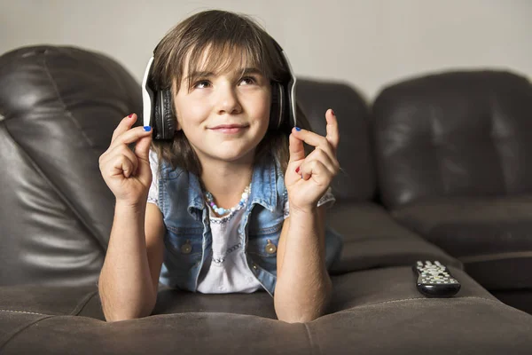 Ragazza di 7 anni che ascolta musica sul divano — Foto Stock