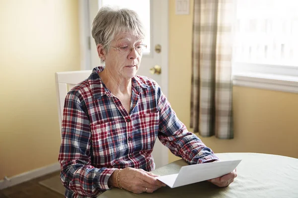 Пожилая женщина беспокоится о счетах уведомления дома — стоковое фото