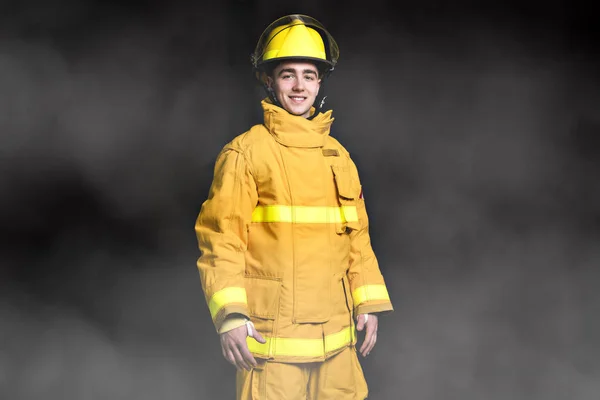 Retrato do bombeiro de pé Cintura para cima estúdio filmado em fundo preto e moke . — Fotografia de Stock