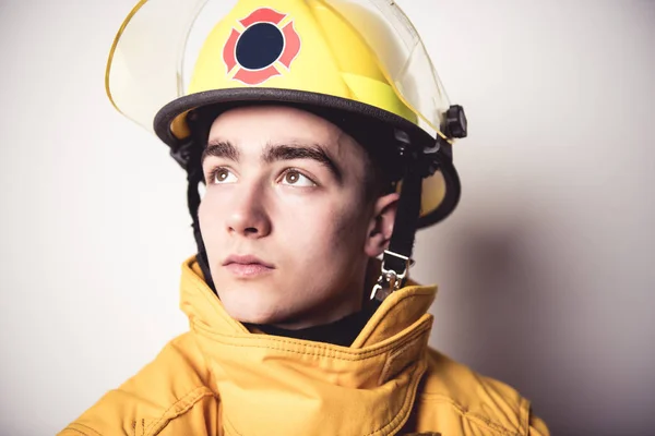 Imagem de um jovem bombeiro na parede branca do estúdio — Fotografia de Stock