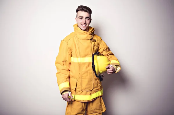 Picture from a young firefighter on studio white wall — Stock Photo, Image