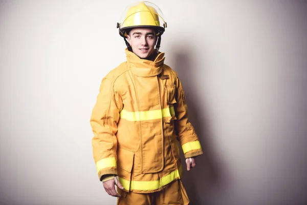 Immagine da un giovane vigile del fuoco su un muro bianco studio — Foto Stock