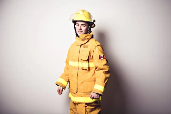 Photo d'un jeune pompier sur un mur blanc studio — Photo