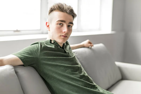 Bonito jovem confiante relaxando em casa no sofá — Fotografia de Stock