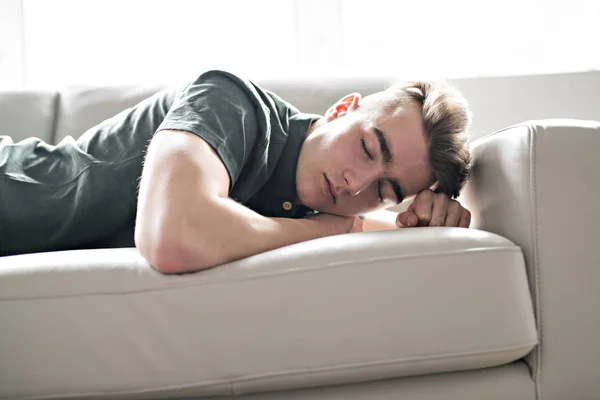 Молодой человек, отдыхающий дома на диване, чувствует себя подавленным — стоковое фото