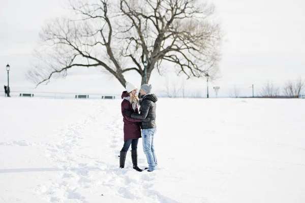 Молодая пара на улице зимой с деревом на спине — стоковое фото