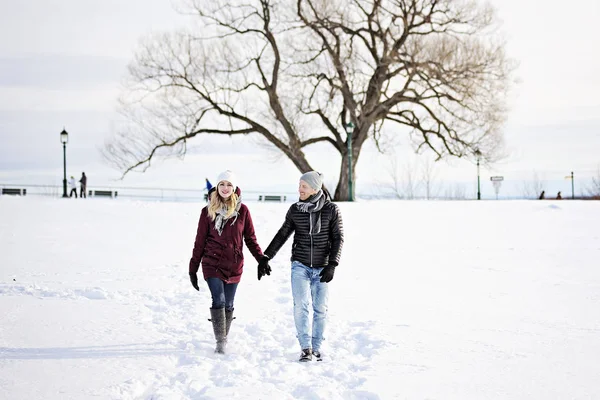 Um jovem casal lá fora no inverno com árvore na parte de trás — Fotografia de Stock