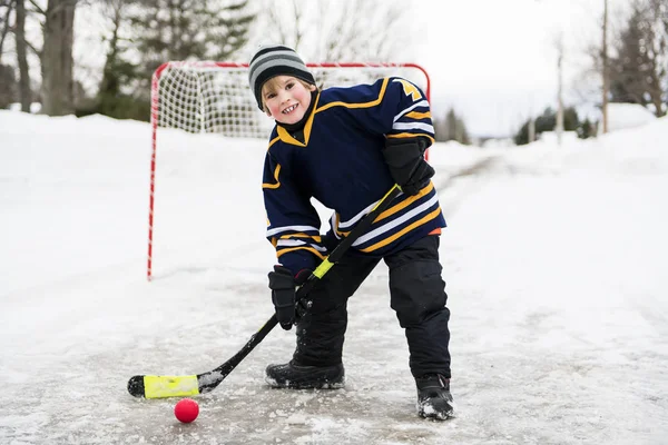 Дитина грає в хокей на вулиці в зимовий сезон — стокове фото