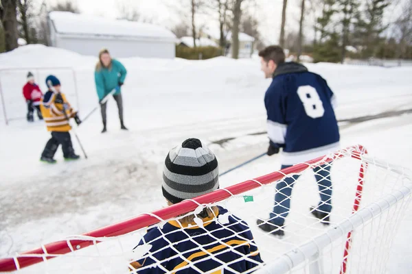 Щасливі смішні діти грають в хокей з батьком і матір'ю на вулиці в зимовий сезон — стокове фото