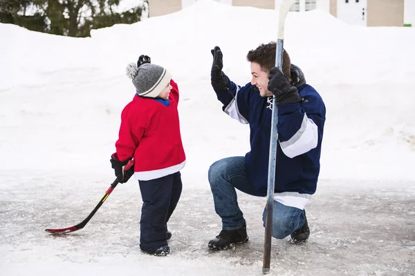 Крутий батько і син розважаються граючи в хокей — стокове фото