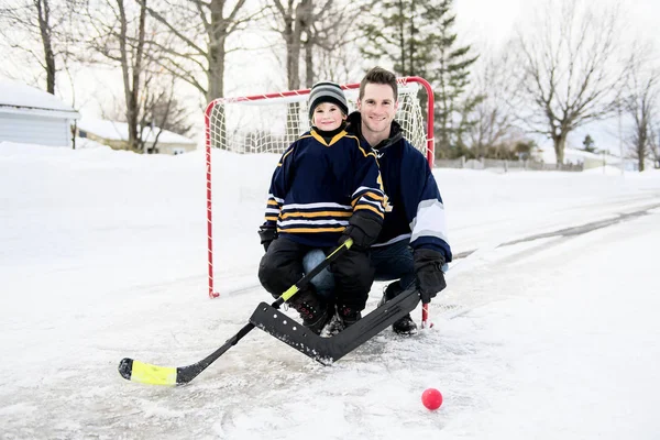 Батько і син розважаються граючи в хокей — стокове фото