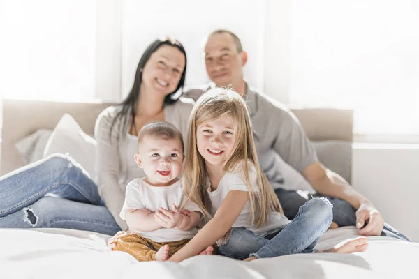 Família feliz na cama branca no quarto — Fotografia de Stock