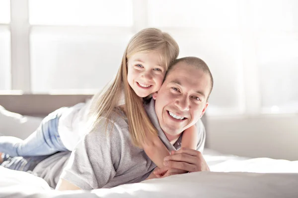 Vader en dochter genietend van tijd in witte bed — Stockfoto