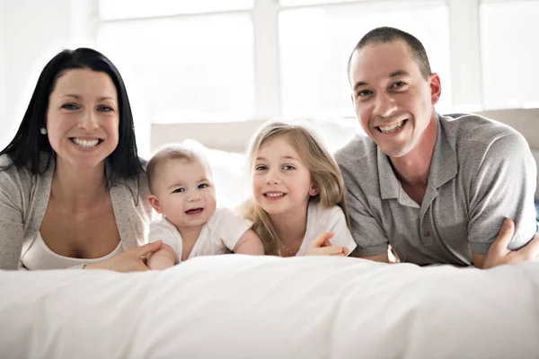 Heureux famille sur lit blanc dans la chambre — Photo
