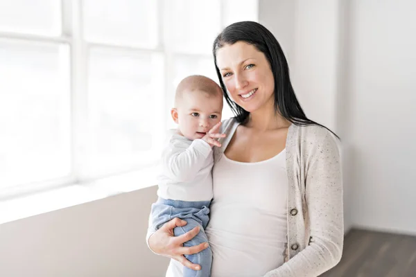 Мама держит ребенка в красивой комнате с белым окном — стоковое фото