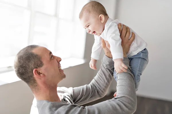 Padre sostiene al bebé en una hermosa habitación con ventanas blancas —  Fotos de Stock