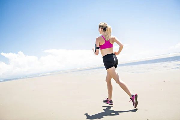 Jovem mulher correndo na praia no dia de verão. atleta corredor exercitando-se ativamente no dia ensolarado — Fotografia de Stock