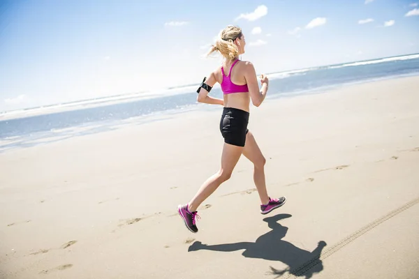 Mujer joven corriendo en la playa en el día de verano. Corredor atleta haciendo ejercicio activamente en el día soleado —  Fotos de Stock