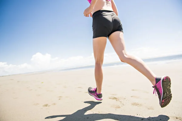 若い女性は、夏の日にビーチでジョギングします。晴れた日で積極的に運動競技ランナー — ストック写真