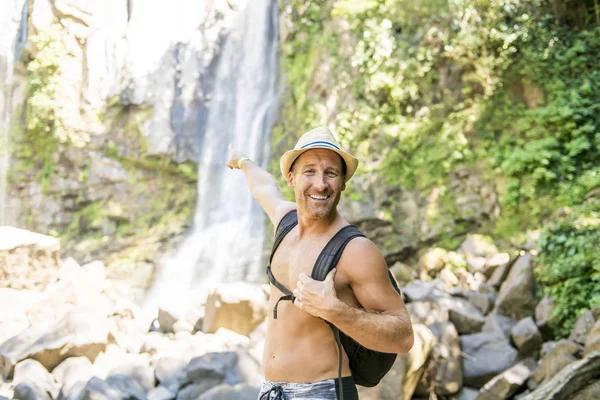 Homme attrayant debout près des cascades sur son dos — Photo