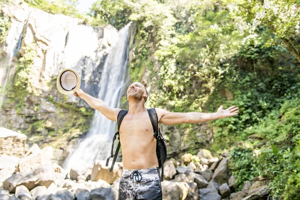 Homme attrayant debout près des cascades sur son dos — Photo