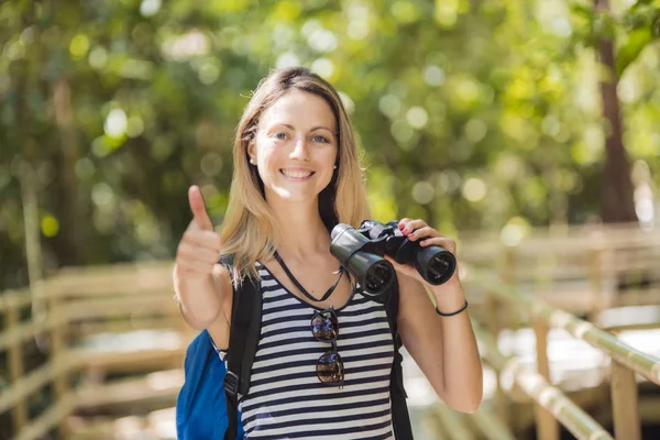 Tourists woman with Binoculars Looking for something along the forest — Stock Photo, Image