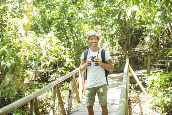 Tourists man with Binoculars Looking for something along the forest — Stock Photo, Image