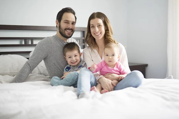 Quatro povos família em uma cama branca . — Fotografia de Stock