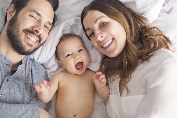 Madre padre e hijo bebé en una cama blanca. — Foto de Stock