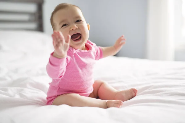 Bebê menina sentar na folha branca no quarto — Fotografia de Stock
