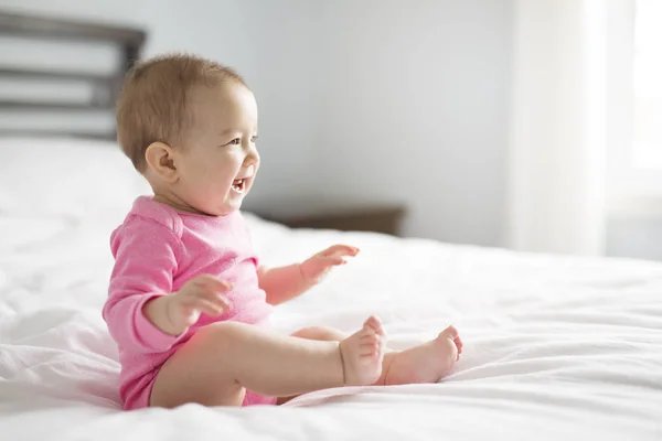 여자 아기 침실에 하얀 시트에 앉아 — 스톡 사진