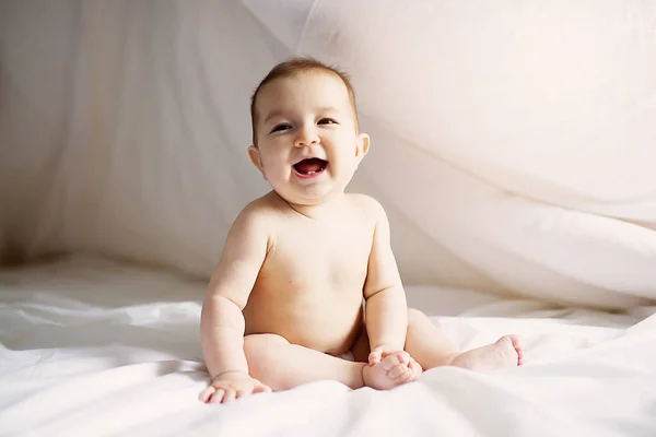 Baby girl siedzieć na białym prześcieradłem na sypialni — Zdjęcie stockowe