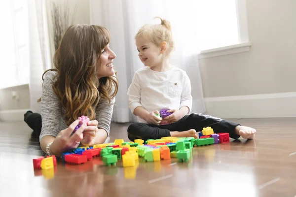 Mor och barn dotter byggnad från leksak block hemma — Stockfoto