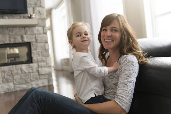 Madre feliz con su hija pequeña en la sala de estar en casa — Foto de Stock