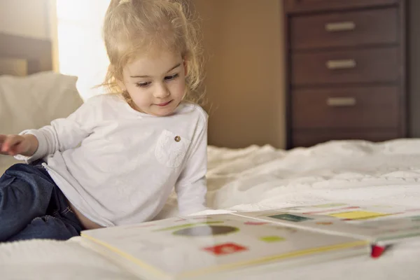 Petite fille mignonne livre de lecture sur le lit — Photo