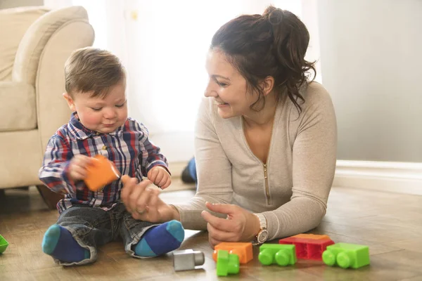 Mor och barn pojke byggnad från leksak block hemma — Stockfoto