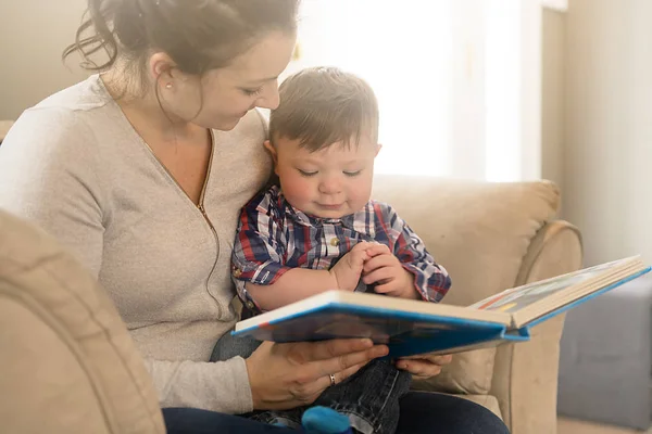 Мама читает книгу со своим ребенком на диване — стоковое фото
