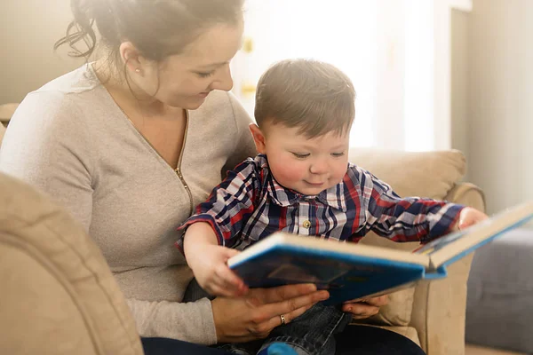 Anya olvasókönyv gyermekével a kanapé — Stock Fotó