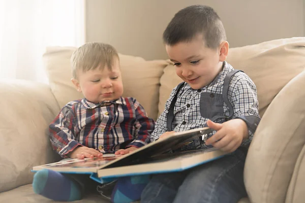 Deux frères assis embrassant sur le canapé lire un livre — Photo