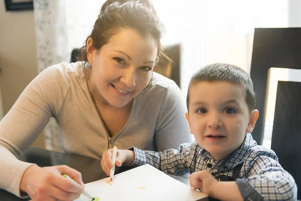 Mère et fils dessinent ensemble à la maison sur la table de cuisine — Photo