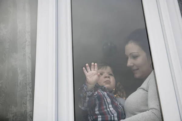 Мать и ребенок сына глядя в окно снаружи — стоковое фото